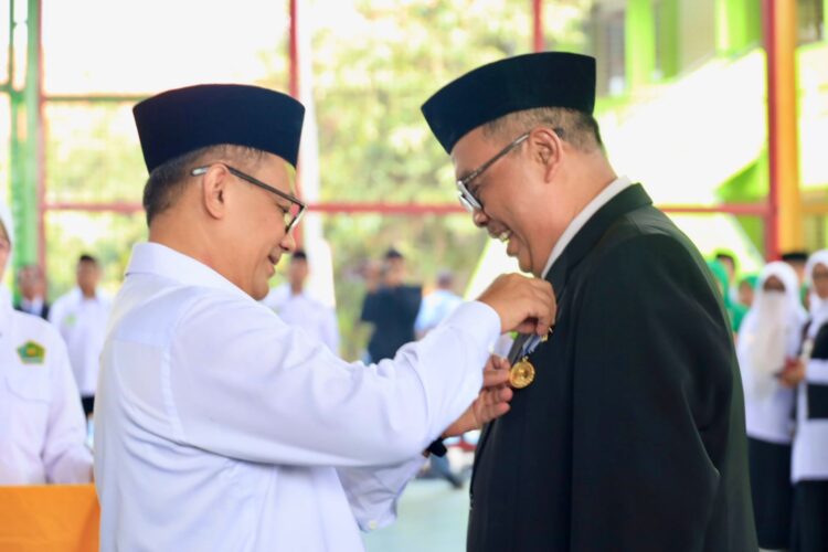 Pj. Walikota Bekasi Gani Muhamad menyematkan lencana kepada Endang Syaefudin ASN Kemenag penghargaan masa kerja. (Foto: humaskotabekasi)