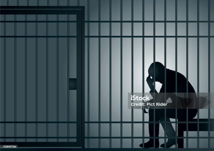 Concept of prison and arrest of an offender or criminal, with a prisoner sitting in his cell holding his head in his hands.